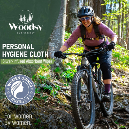 Woman riding bicycle in forest with Woodsy Outfitters outdoor lifestyle branding
